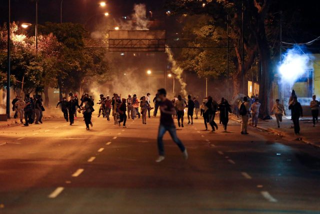 Anti-government demonstrators run from tear gas during clashes with riot police at Altamira Square in Caracas