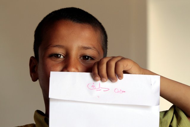 Un niño sirio posa con un papel en el que escribió su nombre por primera vez en una escuela de campo de refugiados en la ciudad de Anjar en el valle de Bekaa en el Líbano 19 de mayo 2014. Foto tomada el 19 de mayo de 2014. REUTERS / Caren Firouz