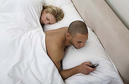 Young man using his cell phone in bed