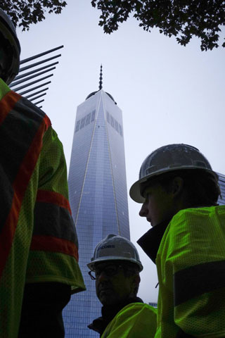 Construction workers walk next to the One World Trade Center in New York