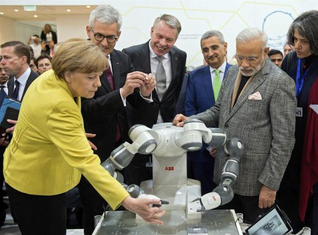 La canciller alemana, Angela Merkel (i), y el primer ministro indio, Narendra Modi (d), observan el robot "YuMi" durante la inauguración de la Feria de Hannover (Alemania), hoy, lunes 13 de abril de 2015. La de Hannover es la feria más importante del mundo del sector industrial, con alrededor de 6.500 empresas de unos 70 países que exponen sus productos, de las que 400 proceden de la India, según cifras aportadas por la organización. EFE/JULIAN STRATENSCHULTE