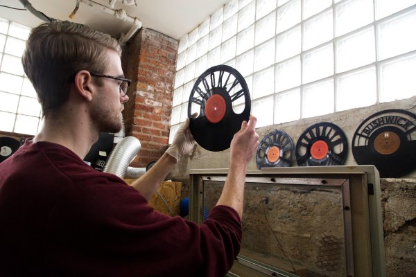 En esta imagen tomada el 12 de marzo de 2015, Will Haude examina un disco modificado con un láser en  Wrecords By Monkey, en el barrio neoyorquino de Brooklyn. La empresa corta y da forma a los discos para hacer joyas, relojes, objetos decorativos y otros productos. (AP Foto/Mark Lennihan)