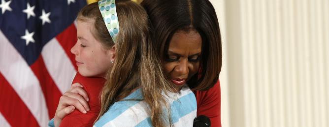 Una niña entrega a Michelle Obama el currículum de su padre desempleado