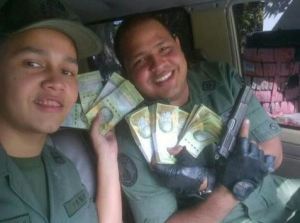 “Foto pal Face” de dos felices GNB, pistola afuera, con pacas de billetes