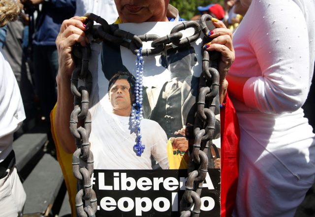 A supporter of jailed opposition leader Lopez hold a poster of him during a gathering to protest against and mark the first anniversary of Lopez's imprisonment, in Caracas