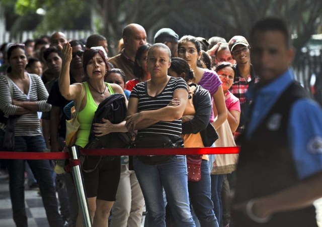 People await in a popular market to buy food in Caracas on December 4, 2015. For the first time in 16 years of "Bolivarian revolution" under late president Hugo Chavez and his successor Nicolas Maduro, polls show their rivals could now win a majority in the National Assembly. AFP PHOTO / LUIS ROBAYO / AFP / LUIS ROBAYO
