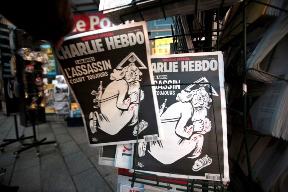 Un hombre toma una copia de la última edición del semanario satírico Charlie Hebdo, con el título "Un año después, el asesino aún está prófugo", en un kiosco en Niza, Francia, 6 de enero de 2016. El periódico del Vaticano criticó al semanario satírico francés Charlie Hebdo por llevar en su portada una caricatura de Dios como un asesino que porta un fusil Kalashnikov, que calificó de "lamentable" e irrespetuosa con fieles de todos los credos. REUTERS/Eric Gaillard