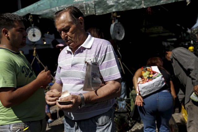 A man counts bolivar notes to pay for his goods, at a vegetable street market in Caracas January 16, 2016. Venezuela's socialist government decreed an "economic emergency" on Friday that will expand its powers and published the first data in a year that shows the depth of a recession fueled by low oil prices and a sputtering state-led model. The central bank, which has been lambasted by critics of President Nicolas Maduro's government for hiding statistics since the end of 2014, said the South American OPEC nation's economy shrank 4.5 percent in the first nine months last year. Inflation soared in that period to an annual rate of 141.5 percent, the world's worst. REUTERS/Carlos Garcia Rawlins