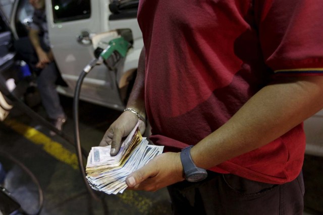 A worker counts Bolivar notes at a gas station which belongs to PDVSA in Caracas February 17, 2016. REUTERS/Marco Bello