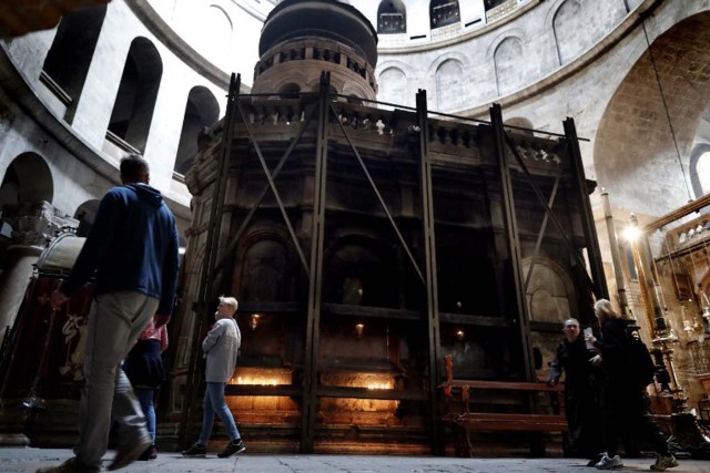 Christian worshippers walk past the Tomb of Christ, where according to Christian belief the body of Jesus was laid after his death, inside the Church of the Holy Sepulchre in the Jerusalem's Old City, on March 23, 2016.  The Churches of the Holy Land announced they will begin the restoration of the seriously dilapitated Tomb of Christ, in the Church of the Holy Sepulchre in Jerusalem in a few weeks. / AFP / THOMAS COEX