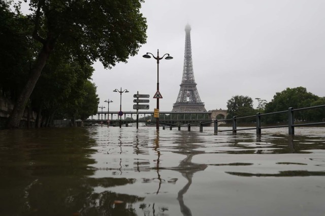 A picture taken on June 2, 2016 shows the river Seine bursting its banks next to the Eiffel Tower in Paris. Officials were putting up emergency flood barriers on June 2 along the swollen river Seine after days of torrential rain -- including near the Louvre, home to priceless works of art. AFP PHOTO / KENZO TRIBOUILLARD / AFP PHOTO / KENZO TRIBOUILLARD
