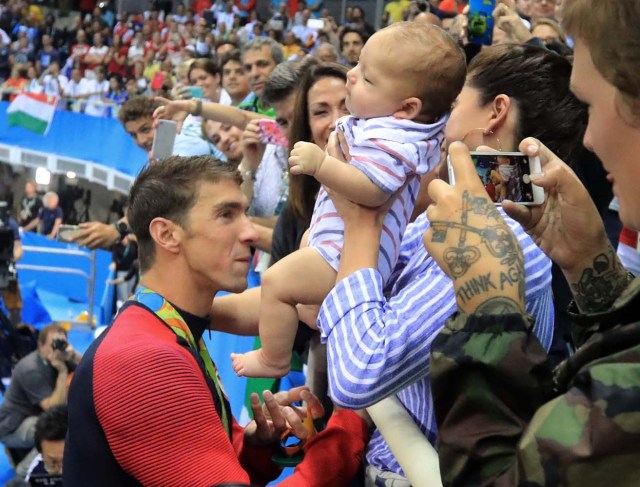 2016 Rio Olympics - Swimming - Victory Ceremony - Men's 200m Butterfly Victory Ceremony - Olympic Aquatics Stadium - Rio de Janeiro, Brazil - 09/08/2016. Michael Phelps (USA) of USA greents his fiance Nicole Johnson and their son Boomer after he won the gold medal.   REUTERS/Dominic Ebenbichler FOR EDITORIAL USE ONLY. NOT FOR SALE FOR MARKETING OR ADVERTISING CAMPAIGNS.