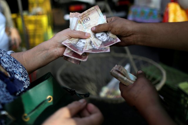 A cashier receives Venezuelan bolivar notes from a customer at a street market in downtown Caracas, Venezuela, December 12, 2016. REUTERS/Ueslei Marcelino
