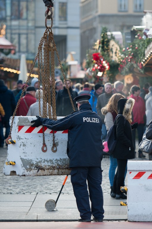 A policeman places concrete elements in front of the "Striezelmarkt" Christmas market in Dresden, eastern Germany, on December 20, 2016, as security measures are taken after a deadly rampage by a lorry driver at a Berlin Christmas market. German Chancellor Angela Merkel said that authorities believe the rampage, killing 12, was a "terrorist" attack likely committed by an asylum seeker. / AFP PHOTO / dpa / Arno Burgi / Germany OUT