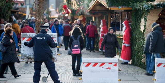 A policeman places concrete elements in front of the "Striezelmarkt" Christmas market in Dresden, eastern Germany, on December 20, 2016, as security measures are taken after a deadly rampage by a lorry driver at a Berlin Christmas market. German Chancellor Angela Merkel said that authorities believe the rampage, killing 12, was a "terrorist" attack likely committed by an asylum seeker. / AFP PHOTO / dpa / Arno Burgi / Germany OUT