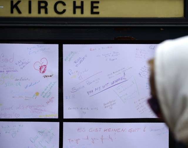 A woman reads a boeard with messages left by people in front at the Kaiser-Wilhelm-Gedaechtniskirche (Kaiser Wilhelm Memorial Church), the day after an attack at the nearby Christmas market in central Berlin, on December 20, 2016. German police said they were treating as "a probable terrorist attack" the killing of 12 people when the speeding lorry cut a bloody swath through the packed Berlin Christmas market. / AFP PHOTO / Tobias SCHWARZ