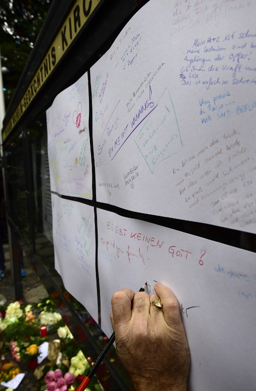 A woman signs a condolence board in front at the Kaiser-Wilhelm-Gedaechtniskirche (Kaiser Wilhelm Memorial Church), the day after an attack at the nearby Christmas market in central Berlin, on December 20, 2016. German police said they were treating as "a probable terrorist attack" the killing of 12 people when the speeding lorry cut a bloody swath through the packed Berlin Christmas market. / AFP PHOTO / Tobias SCHWARZ