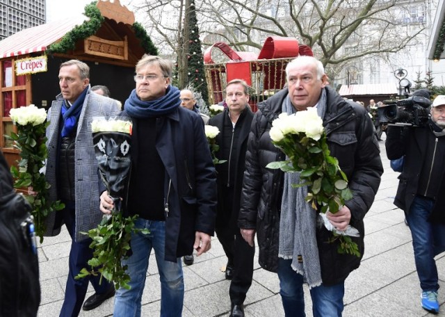 Market salesmen arrive with flowers at the Christmas market near the Kaiser-Wilhelm-Gedaechtniskirche (Kaiser Wilhelm Memorial Church), the day after an attack, in central Berlin, on December 20, 2016. German police said they were treating as "a probable terrorist attack" the killing of 12 people when the speeding lorry cut a bloody swath through the packed Berlin Christmas market. / AFP PHOTO / Tobias SCHWARZ