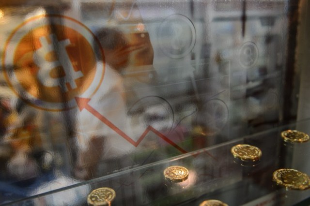 (FILES) This file photo taken on August 3, 2016 shows a man walking past a display cabinet containing models of Bitcoins in Hong Kong. Bitcoin neared its all-time high on January 5, 2017 with the surging digital currency tipped to become a new safe haven asset as the world grapples with growing economic uncertainty. / AFP PHOTO / Anthony WALLACE