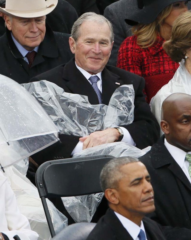 Former President George W. Bush takes off his cover under the rain during the inauguration ceremonies swearing in Donald Trump as the 45th president of the United States on the West front of the U.S. Capitol in Washington, U.S., January 20, 2017. REUTERS/Rick Wilking