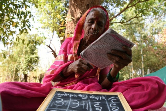 This photo taken on March 1, 2017 shows Indian grandmother Sulochona Kedar, 68, reading from a textbook during a class at Aajibaichi Shala, or "school for grannies" in the local Marathi language, in Phangane village in Maharashtra state's Thane district, some 125km northeast of Mumbai. They wear uniforms, carry satchels, and eagerly recite the alphabet in class, but the students here are different -- this is a "school for grannies". Deprived of an education as children, the women -- most of whom are widows and aged between 60 and 90 -- are finally fulfilling a life-long dream to become literate through this unique initiative near Mumbai. / AFP PHOTO / Indranil MUKHERJEE / TO GO WITH "India-education-women-school,FEATURE" by Peter HUTCHISON
