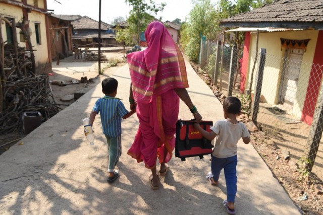 This photo taken on March 1, 2017 shows Savita Kedar being accompanied by her grandchildren as she walks home after attending class at the Aajibaichi Shala, or "school for grannies" in the local Marathi language, in Phangane village in Maharashtra state's Thane district, some 125km northeast of Mumbai. They wear uniforms, carry satchels, and eagerly recite the alphabet in class, but the students here are different -- this is a "school for grannies". Deprived of an education as children, the women -- most of whom are widows and aged between 60 and 90 -- are finally fulfilling a life-long dream to become literate through this unique initiative near Mumbai. / AFP PHOTO / Indranil MUKHERJEE / TO GO WITH "India-education-women-school,FEATURE" by Peter HUTCHISON