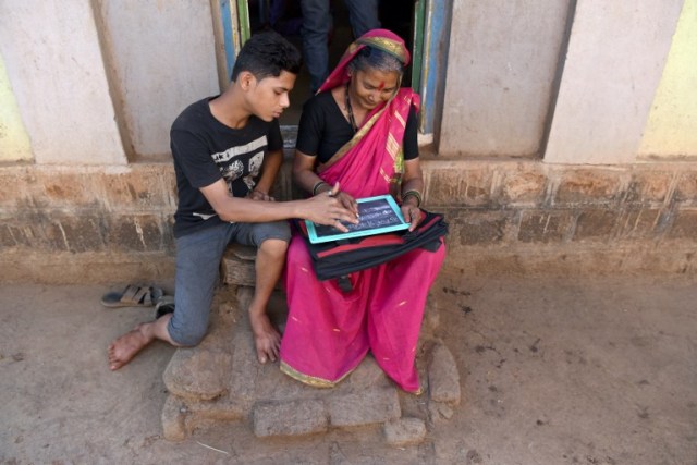This photo taken on March 1, 2017 shows Aniket Kedar, 15, helping his grandmother Gulab Kedar complete her homework at the Aajibaichi Shala, or "school for grannies" in the local Marathi language, in Phangane village in Maharashtra state's Thane district, some 125km northeast of Mumbai. They wear uniforms, carry satchels, and eagerly recite the alphabet in class, but the students here are different -- this is a "school for grannies". Deprived of an education as children, the women -- most of whom are widows and aged between 60 and 90 -- are finally fulfilling a life-long dream to become literate through this unique initiative near Mumbai. / AFP PHOTO / Indranil MUKHERJEE / TO GO WITH "India-education-women-school,FEATURE" by Peter HUTCHISON