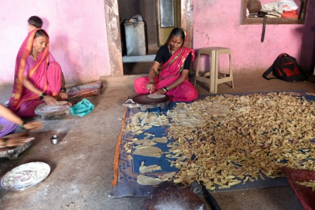 This photo taken on March 1, 2017 shows Indian grandmother Draupada Kedar, 62, and Gulab Kedar, 62, making papads at home after attending class at Aajibaichi Shala, or "school for grannies" in the local Marathi language, in Phangane village in Maharashtra state's Thane district, some 125km northeast of Mumbai. They wear uniforms, carry satchels, and eagerly recite the alphabet in class, but the students here are different -- this is a "school for grannies". Deprived of an education as children, the women -- most of whom are widows and aged between 60 and 90 -- are finally fulfilling a life-long dream to become literate through this unique initiative near Mumbai. / AFP PHOTO / Indranil MUKHERJEE / TO GO WITH "India-education-women-school,FEATURE" by Peter HUTCHISON