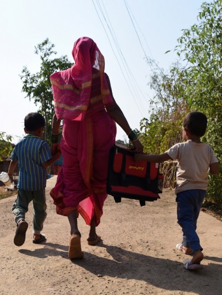 This photo taken on March 1, 2017 shows Indian grandmother Savita Kedar being accompanied by her grandchildren as she walks home from Aajjibaichi Shala, or "school for grannies" in the local Marathi language, in Phangane village in Maharashtra state's Thane district, some 125km northeast of Mumbai. They wear uniforms, carry satchels, and eagerly recite the alphabet in class, but the students here are different -- this is a "school for grannies". Deprived of an education as children, the women -- most of whom are widows and aged between 60 and 90 -- are finally fulfilling a life-long dream to become literate through this unique initiative near Mumbai. / AFP PHOTO / Indranil MUKHERJEE / TO GO WITH "India-education-women-school,FEATURE" by Peter HUTCHISON