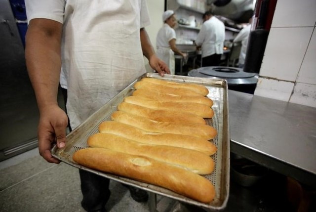 Foto de archivo: Un empleado lleva una bandeja de pan recién horneado dentro de una panadería en el centro de Caracas, Venezuela, 15 de septiembre del 2016. El Gobierno de Venezuela ordenó el arresto de cuatro personas y amenazó con tomar el control de varias panaderías para combatir lo que el presidente socialista Nicolás Maduro ha calificado como una "guerra del pan", orquestada para privar a las personas del alimento fundamental. REUTERS/Henry Romero