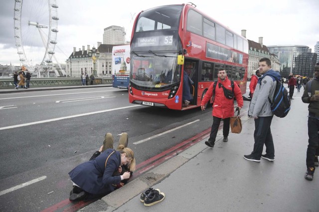 A woman assist an injured person after an incident on Westminster Bridge in London, March 22, 2017. REUTERS/Toby Melville TPX IMAGES OF THE DAY