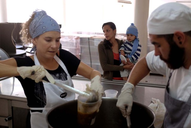 A woman carries her child as she waits for a cup of soup being served by chefs of La Casa Bistro restaurant, members of the "Full Stomach, Happy Heart" (Barriga llena, corazon contento) charity,  at the J.M. de los Rios Children Hospital in Caracas, Venezuela February 13, 2017. Picture taken February 13, 2017. REUTERS/Marco Bello