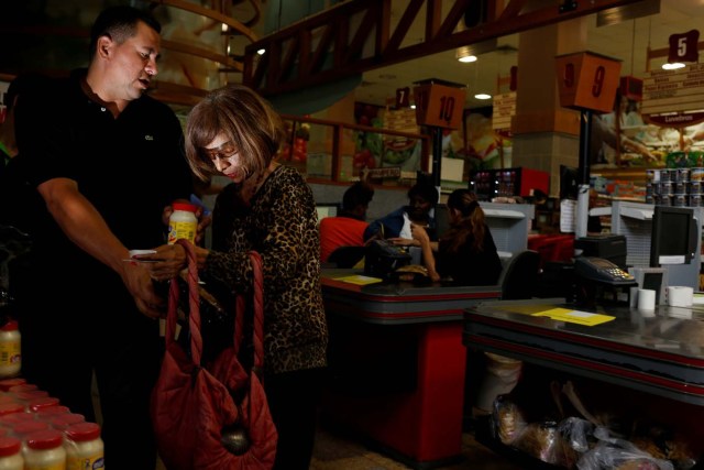 A woman receives a jar of mayonnaise and packet of pasta from a worker after she queued outside a supermarket in Caracas, Venezuela March 10, 2017. REUTERS/Carlos Garcia Rawlins SEARCH "GARCIA QUEUEING" FOR THIS STORY. SEARCH "WIDER IMAGE" FOR ALL STORIES.