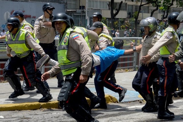 Police carry a demonstrator under arrest during a protest against President Nicolas Maduro's government in Caracas on April 4, 2017.  Activists clashed with police in Venezuela Tuesday as the opposition mobilized against moves to tighten President Nicolas Maduro's grip on power. Protesters hurled stones at riot police who fired tear gas as they blocked the demonstrators from advancing through central Caracas, where pro-government activists were also planning to march. / AFP PHOTO / FEDERICO PARRA