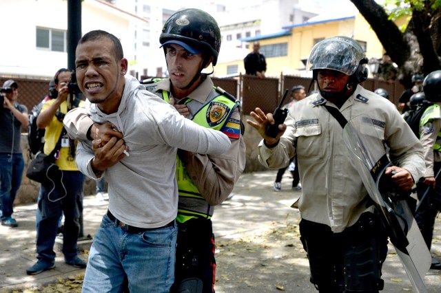 A demonstrator is arrested by riot police during a protest against President Nicolas Maduro's government in Caracas on April 4, 2017.  Activists clashed with police in Venezuela Tuesday as the opposition mobilized against moves to tighten President Nicolas Maduro's grip on power. Protesters hurled stones at riot police who fired tear gas as they blocked the demonstrators from advancing through central Caracas, where pro-government activists were also planning to march. / AFP PHOTO / FEDERICO PARRA
