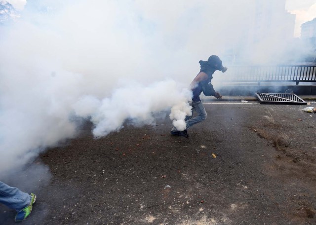 Demonstrators against Nicolas Maduro's government clash with riot police at eastern Caracas on April 8, 2017. The opposition is accusing pro-Maduro Supreme Court judges of attempting an internal "coup d'etat" for attempting to take over the opposition-majority legislature's powers last week. The socialist president's supporters held counter-demonstrations on Thursday, condemning Maduro's opponents as "imperialists" plotting with the United States to oust him. / AFP PHOTO / JUAN BARRETO