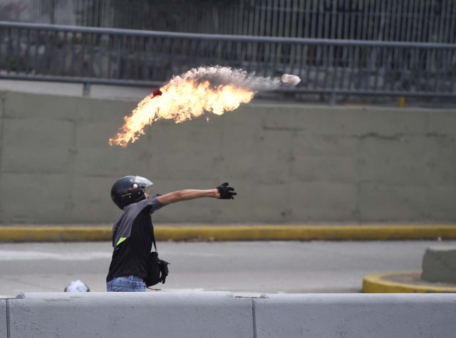 A demonstrator against Nicolas Maduro's government throws a Molotov cocktail during clashes with riot police at eastern Caracas on April 8, 2017. The opposition is accusing pro-Maduro Supreme Court judges of attempting an internal "coup d'etat" for attempting to take over the opposition-majority legislature's powers last week. The socialist president's supporters held counter-demonstrations on Thursday, condemning Maduro's opponents as "imperialists" plotting with the United States to oust him. / AFP PHOTO / JUAN BARRETO