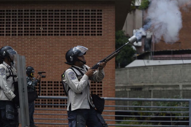 Riot police throw tear gas during clashes with demonstrators against Nicolas Maduro's government in Caracas on April 8, 2017. The opposition is accusing pro-Maduro Supreme Court judges of attempting an internal "coup d'etat" for attempting to take over the opposition-majority legislature's powers last week. The socialist president's supporters held counter-demonstrations on Thursday, condemning Maduro's opponents as "imperialists" plotting with the United States to oust him. / AFP PHOTO / JUAN BARRETO
