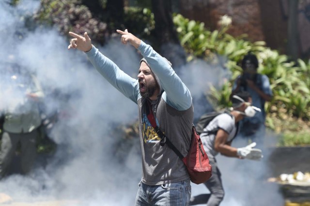 A demonstrator shout slogans against Nicolas Maduro's government during clashes with riot police in Caracas on April 8, 2017. The opposition is accusing pro-Maduro Supreme Court judges of attempting an internal "coup d'etat" for attempting to take over the opposition-majority legislature's powers last week. The socialist president's supporters held counter-demonstrations on Thursday, condemning Maduro's opponents as "imperialists" plotting with the United States to oust him. / AFP PHOTO / JUAN BARRETO