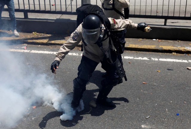 A riot police officer attempts to kick a gas canister during clashes with opposition supporters in Caracas, Venezuela, April 8, 2017. REUTERS/Carlos Garcia Rawlins