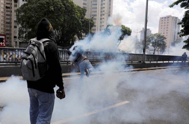 A demonstrator throws back a gas canister during clashes with riot police during a rally in Caracas, Venezuela, April 8, 2017. REUTERS/Carlos Garcia Rawlins