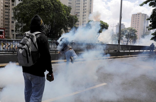 REFILE - CLARIFYING CAPTIONA demonstrator throws back a tear gas canister during clashes with riot police during a rally in Caracas, Venezuela, April 8, 2017. REUTERS/Carlos Garcia Rawlins