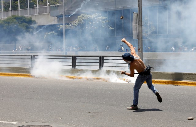 A demonstrators throws a rock during clashes with riot police during a rally in Caracas, Venezuela, April 8, 2017. REUTERS/Carlos Garcia Rawlins