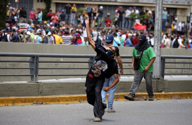 A demonstrator throws a rock during clashes with riot police at a rally in Caracas, Venezuela, April 8, 2017. REUTERS/Carlos Garcia Rawlins
