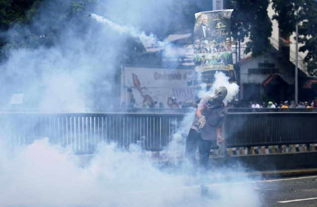 Demonstrator throws back a tear gas canister while clashing with the riot police during a rally in Caracas, Venezuela, April 8, 2017. REUTERS/Marco Bello