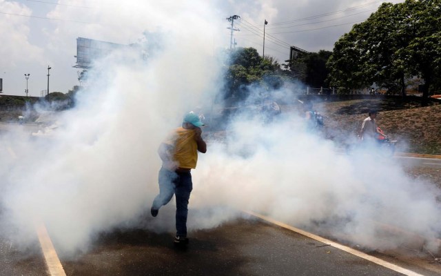 A man runs away from tear gas during a rally against Venezuela's President Nicolas Maduro's government in Caracas, Venezuela April 10, 2017. REUTERS/Carlos Garcia Rawlins