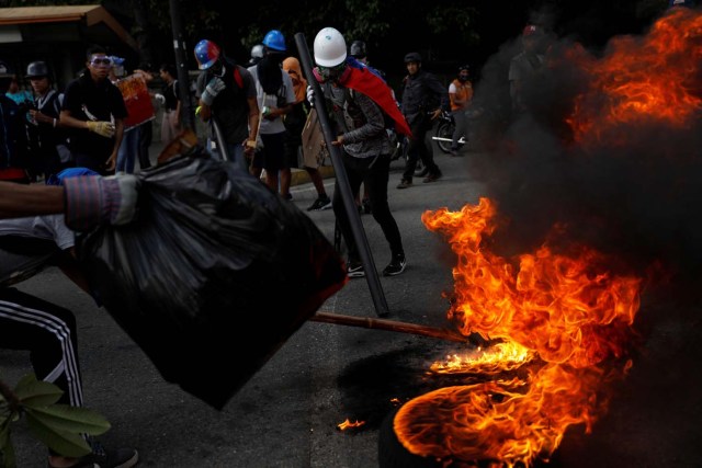 Opposition supporters build a fire barricade while rallying against President Nicolas Maduro in Caracas, Venezuela, May 20, 2017. REUTERS/Carlos Garcia Rawlins