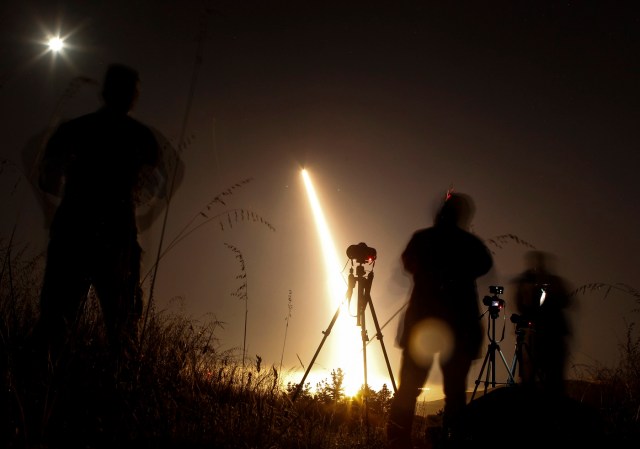 Photographers take pictures of a streak of light trailing off into the night sky as the US military test fires an unarmed intercontinental ballistic missile (ICBM) at Vandenberg Air Force Base, some 130 miles (209 kms) northwest of Los Angeles, California early on May 3, 2017. / AFP PHOTO / RINGO CHIU