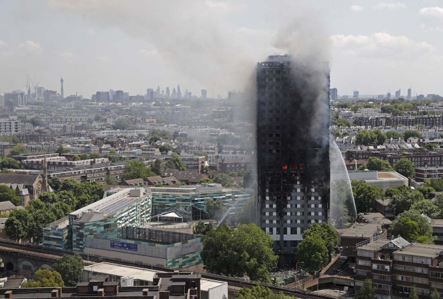 Smoke and flames billows from Grenfell Tower as firefighters attempt to control a blaze at a residential block of flats on June 14, 2017 in west London. At least six people were killed Wednesday when a massive fire tore through a London apartment block in the middle of the night, with witnesses reporting terrified people had leapt from the 24-storey tower. / AFP PHOTO / Adrian DENNIS