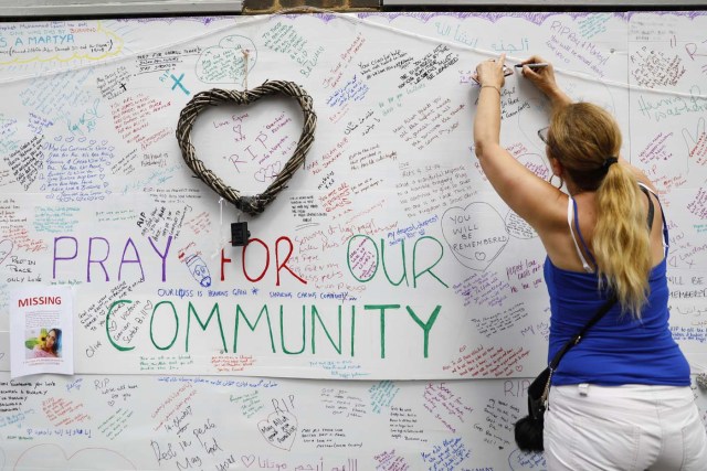 Wellwishers write messages on a wall of condolence following the blaze at Grenfell Tower, a residential tower block in west London on June 15, 2017. Firefighters searched for bodies today in a London tower block gutted by a blaze that has already left 12 dead, as questions grew over whether a recent refurbishment contributed to the fire. / AFP PHOTO / Tolga AKMEN